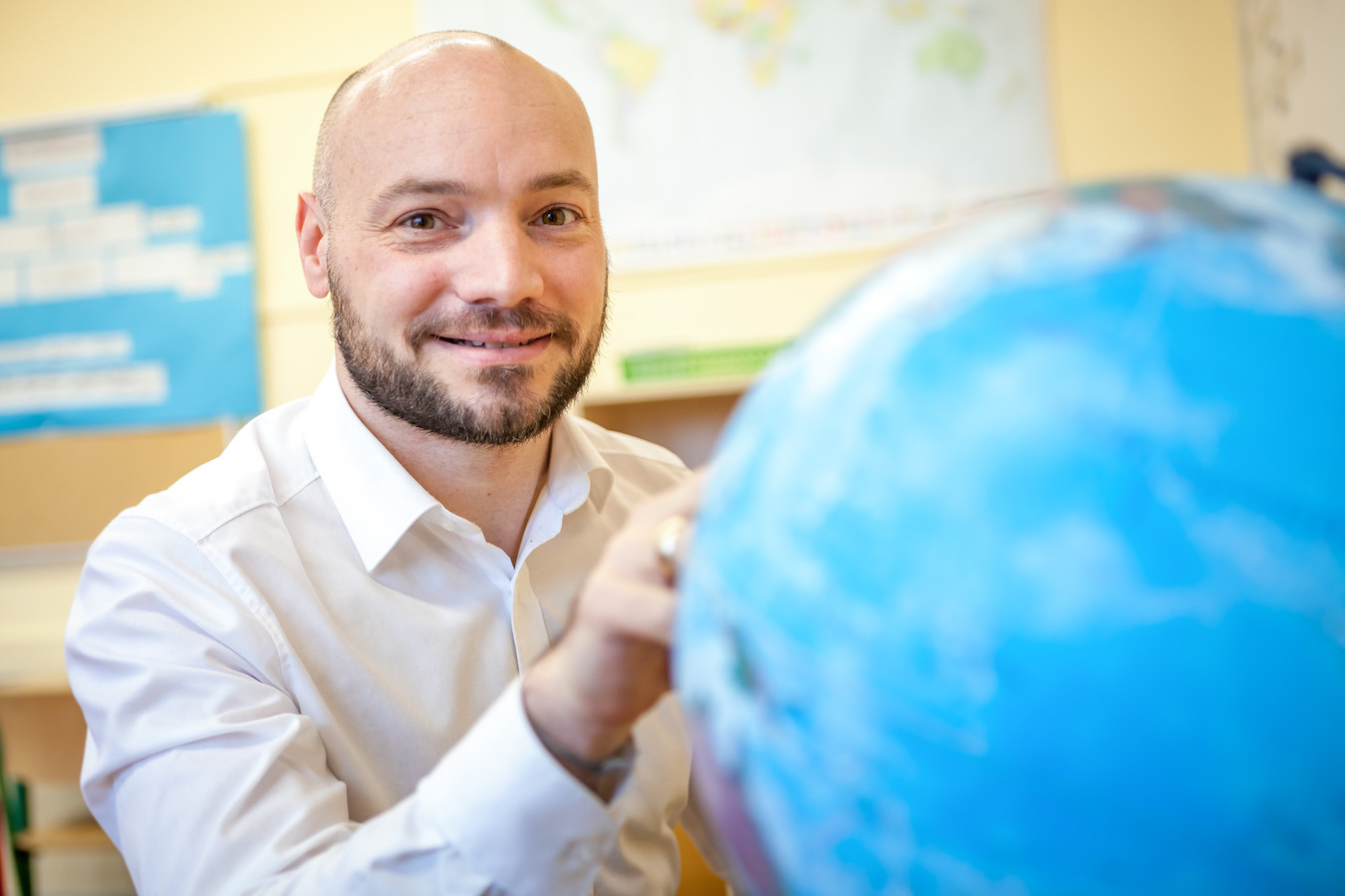 Business Portrait eines jungen Mannes mit Weltkugel im Vordergrund.